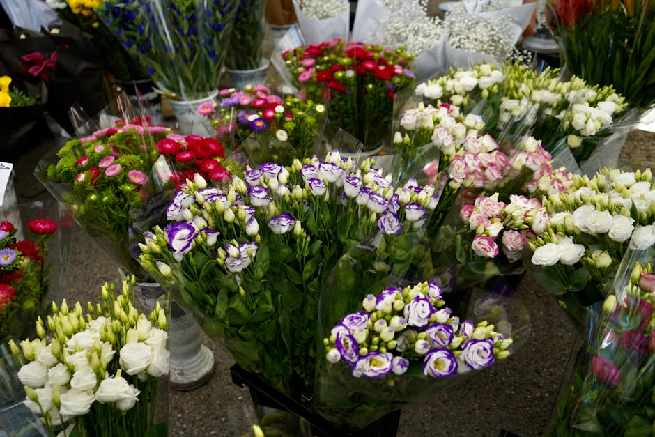 An extensive display of fresh floral arrangements and bouquets showcased on a florist shop table, featuring a variety of flowers such as purple and white irises, pink and white roses, and red and pink